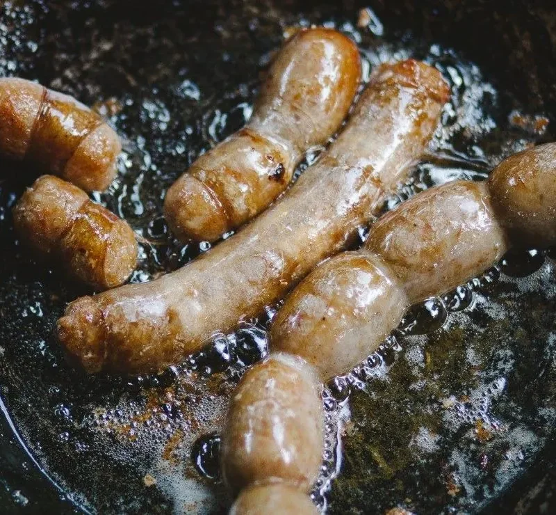 Pork sausages frying in pan